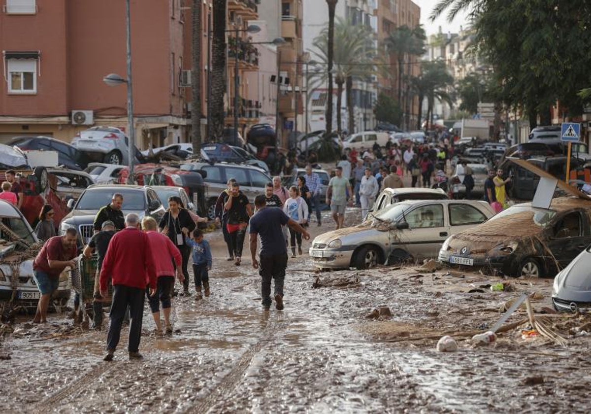 Decenas de personas caminan por una calle embarrada en Paiporta, en la mañana del día 30.