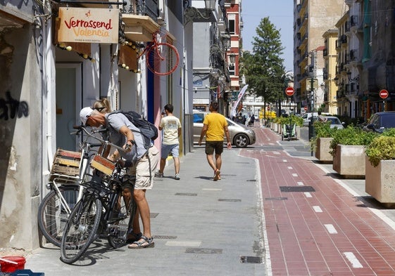 Una persona inspecciona una bicicleta en la puerta de una tienda de alquiler.
