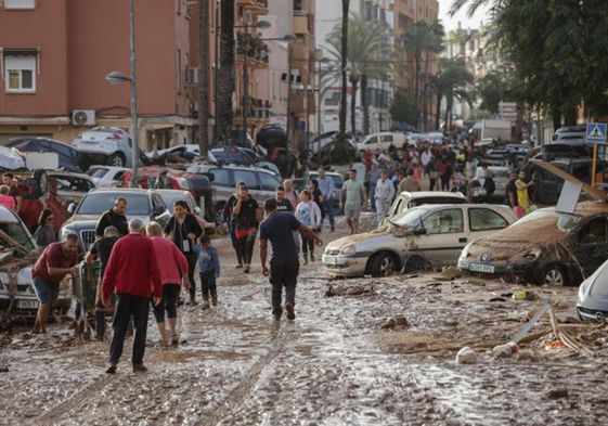 Decenas de personas caminan por una calle embarrada en Paiporta, en la mañana del día 30.