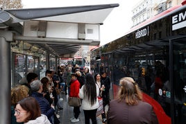 Personas junto a un autobús de la EMT.