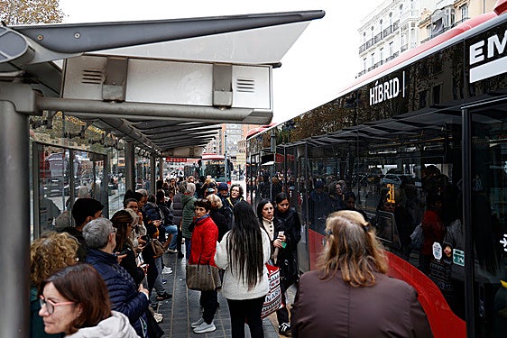 Personas junto a un autobús de la EMT.