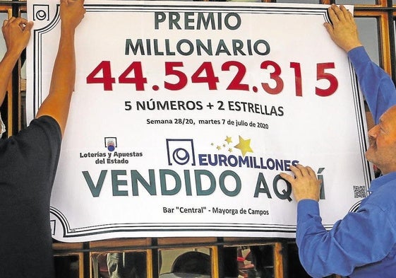 Dos ganadores de un premio de Euromillones cuelgan un cartel. Imagen de archivo.