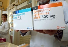 Una farmacéutica muestra una caja de paracetamol y otra de ibuprofeno.