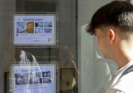 Un joven observa el escaparate de una inmobiliaria.