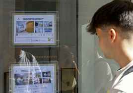 UUnn joven observa los anuncios de una inmobiliaria.
