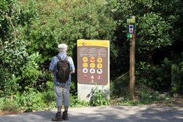 Un visitante mira los carteles que alertan del riesgo de incendio en el Montgó.