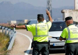 Dos agentes de Tráfico detienen a un vehículo en una carretera.