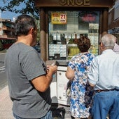 Varias personas hacen cola para comprar un décimo de la ONCE.