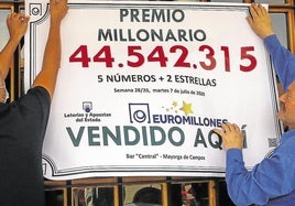 Una pareja ganadora de un premio de Euromillones cuelga un cartel.