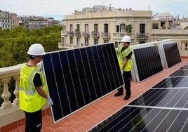Dos trabajadores colocan una placa solar en la terraza de una vivienda.