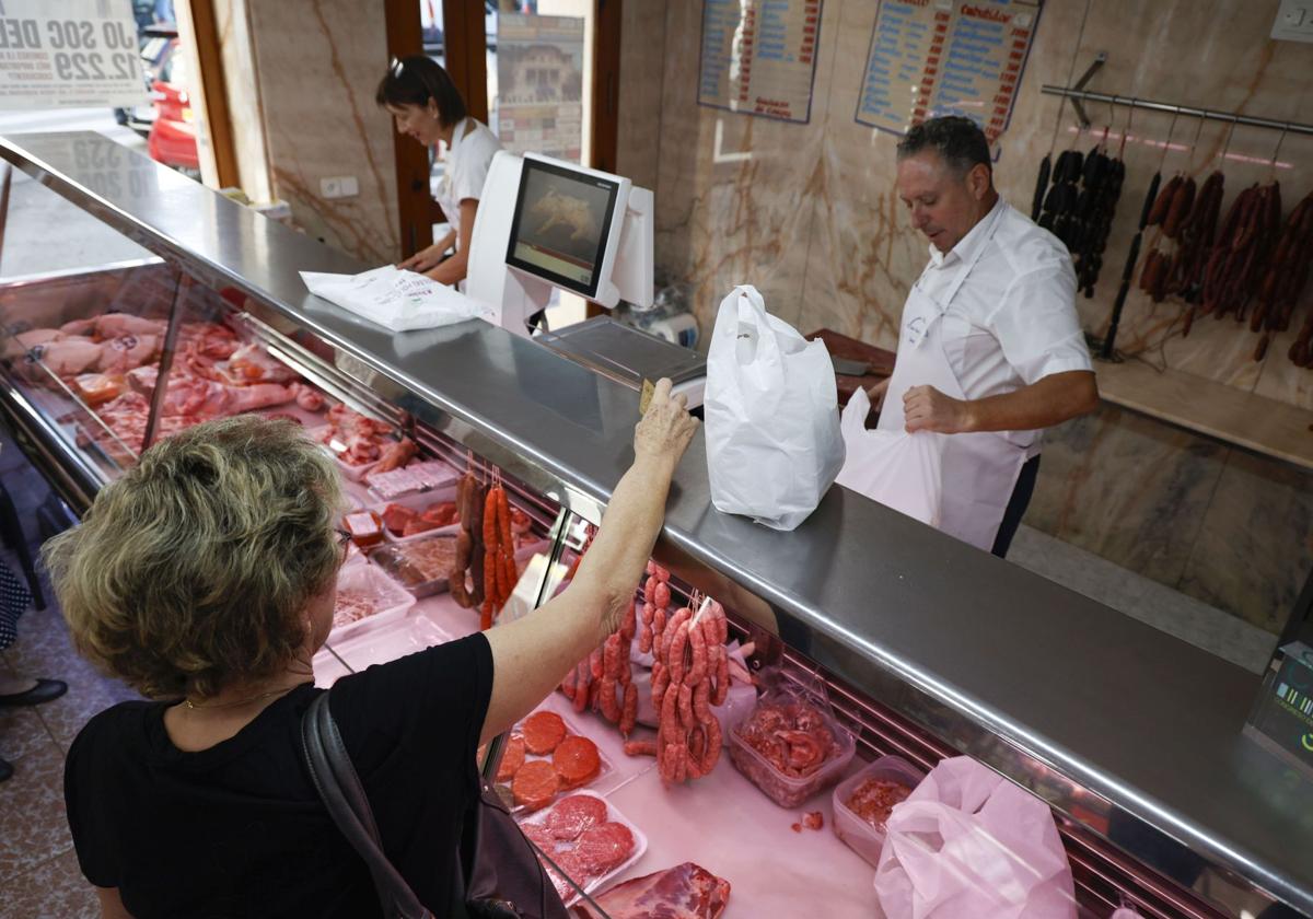 Una clienta recoge su compra en una carnicería de Carcaixent.