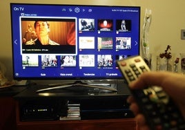 Un hombre sintoniza los canales de su televisor.