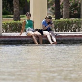 Dos personas se refrescan en una fuente de los jardines del antiguo cauce del Turia para combatir el calor