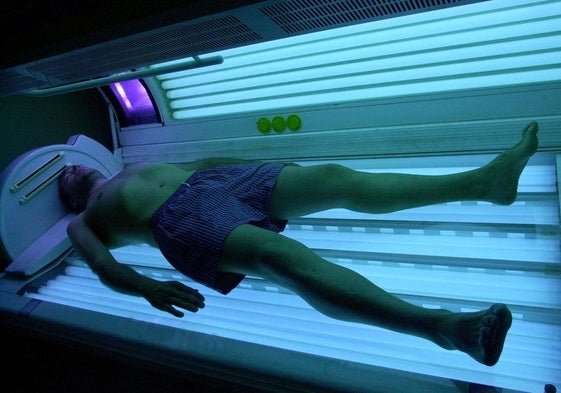 Un hombre se broncea en una cabina de rayos UVA.