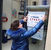 Una empleada de una administración de lotería coloca el cartel anunciador del premio. Imagen de archivo.