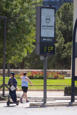 Dos personas caminan por la calle en un día de calor.
