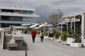 Dos personas pasean por el paseo frente a los restaurantes.