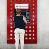 Una mujer saca dinero de un cajero del banco Santander.