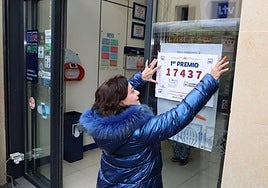 Una empleada de una administración de lotería coloca el cartel anunciador del premio. Imagen de archivo.