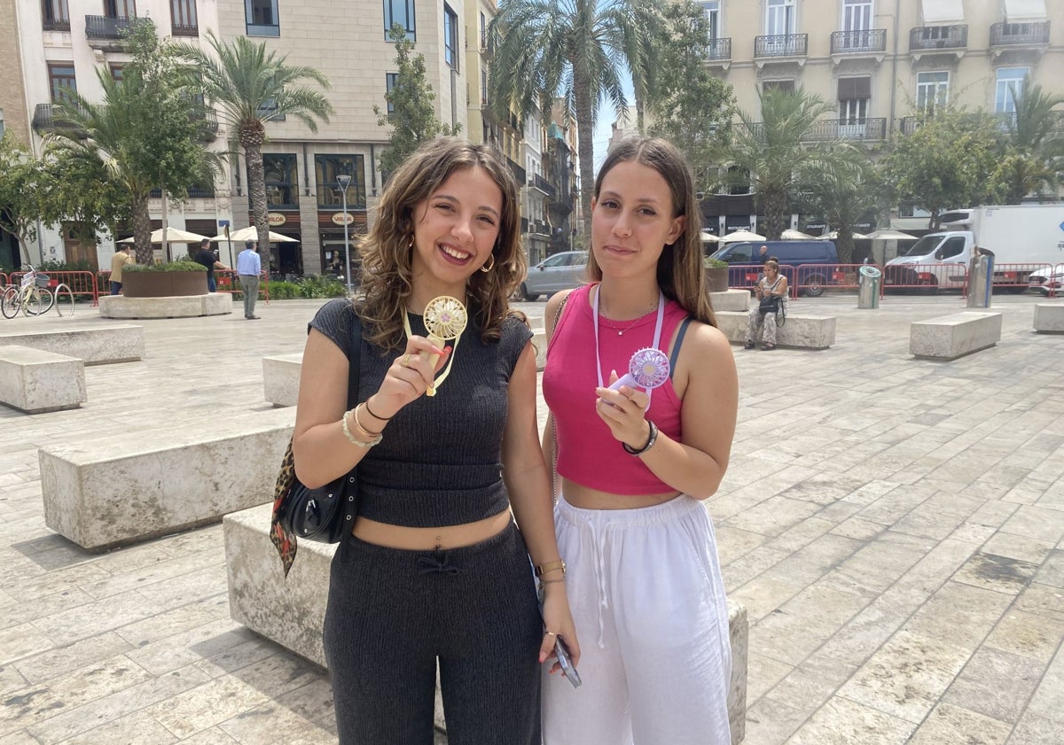 Imagen principal - Las italianas Carlota y Matilde, con un ventilador portátil; Rafael José Pascual, vendiendo abanicos y zona refrescante de la plaza de la Reina.