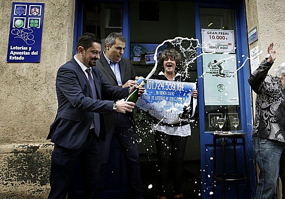 Propietarios de una administración de lotería celebran la entrega de un premio.