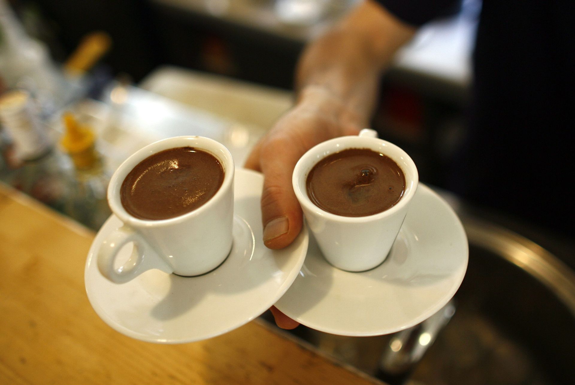 Un camarero sirve dos cafés.
