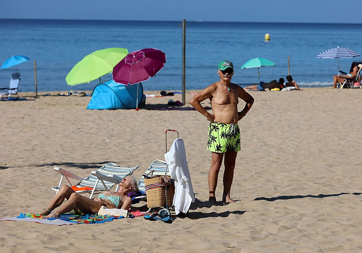 Dos turistas toman el sol en una playa de Benidorm.