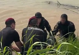 Varios policías sacan el cadáver del agua.