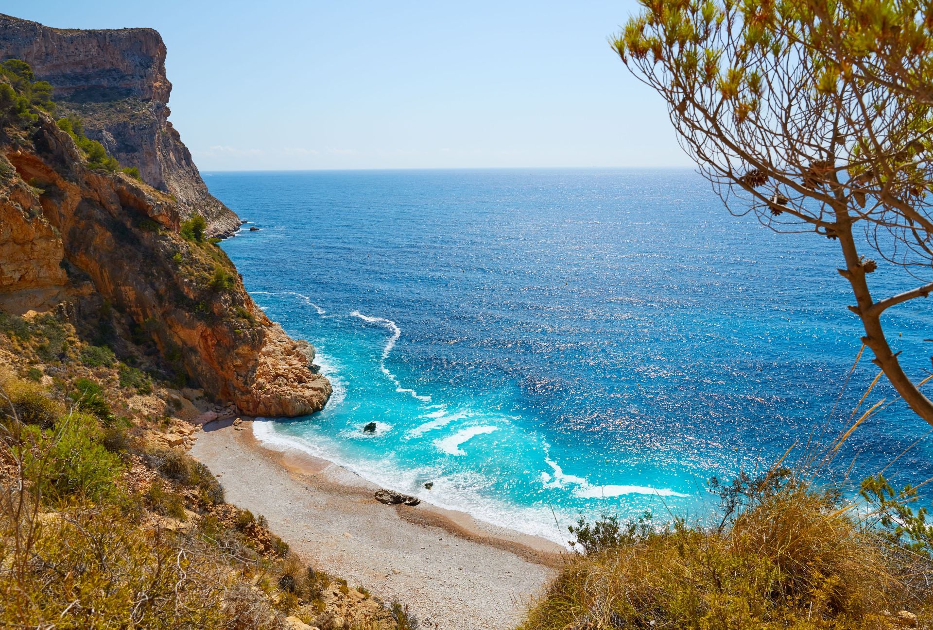 Cala del Moraig, Alicante, Comunitat Valenciana (España). Entre Moraira y Jávea, en el término municipal de Poble Nou de Benitatxell. Se trata de una playa de unos 300 metros de longitud, con grava, arena dirada y «unas aguas cristalinas que invitan a sumergirse», dicen desde Jetcost. Los expertos señalan que «está enclavada en un paraje excepcional, rodeado de acantilados, formaciones rocosas y vegetación, escondida detrás del macizo del Puig Llorença». Sin embargo, advierten: «es una zona visitable, pero hay que extremar las precauciones porque las rocas resbalan». «En su interior hay galerías por las que se adentran submarinistas expertos. Además, en la zona norte de la Cala del Moraig son muchos los usuarios que practican el nudismo», concluyen.