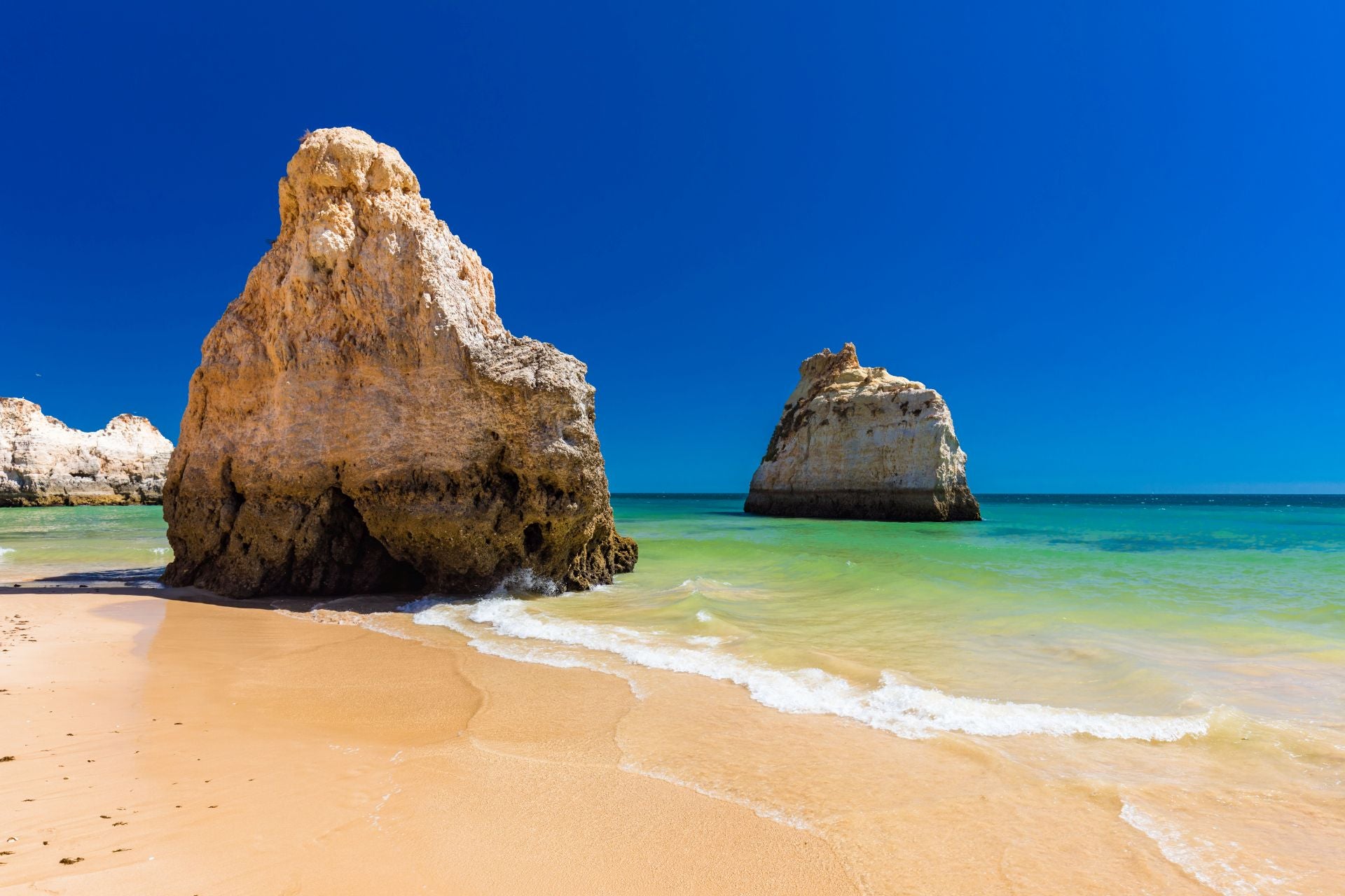 Praia dos Três Irmãos, Algarve (Portugal). Su nombre original es Playa Alvor Nascente. Lo más llamativo son sus tres formaciones rocosas en el lado Este, con altas rocas y acantilados, que se conocen como falesias. Al otro lado tiene dunas que se extienden un kilómetro. «En los meses de julio y agosto suele haber bastante gente, pero no tanto como en las playas más cercanas al centro de Portimão», indican. «El agua suele estar tranquila y por lo tanto es bastante segura para los niños», explican. Además, señalan que «para comer no es necesario ir muy lejos: hay restaurantes en la playa, especializados en ricos arroces y una gran variedad de mariscos y pescados asados con abundante guarnición, pero que también ofrecen otras opciones». Por último, aforman que «después de un día de playa, no hay nada mejor que disfrutar del atardecer y de una cena con vistas al mar y a las bellas puestas de sol».