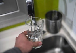 Una persona llena en el grifo un vaso de agua.