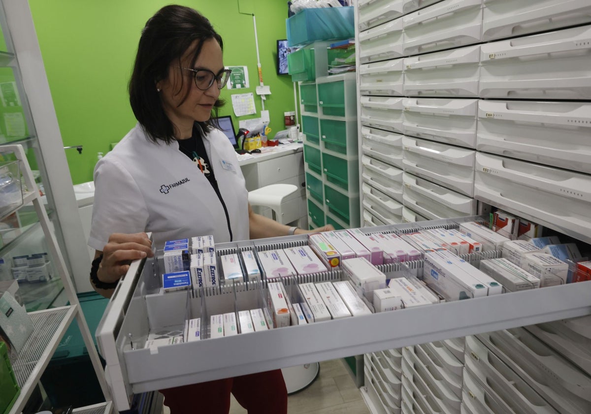 Una farmacéutica revisa los medicamentos en su establecimiento.