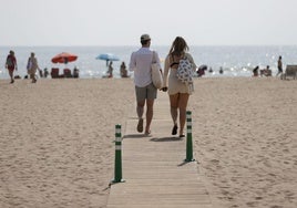 Dos personas pasean en la playa de la Malvarrosa de Valencia