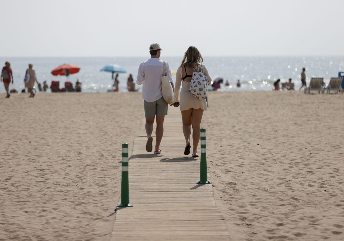 Dos personas pasean en la playa de la Malvarrosa de Valencia