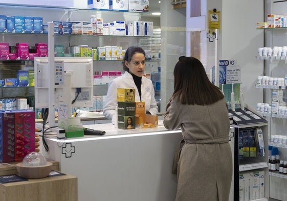 Una farmacéutica atiende a una mujer.
