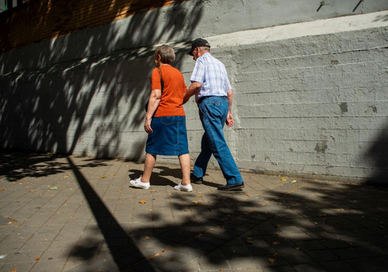 Dos jubilados pasean por una calle.
