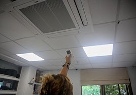 Una mujer enciende el aire acondicionado en una oficina.