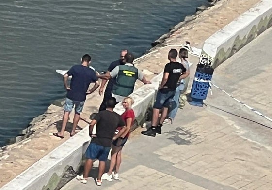 Un guardia civil y varios testigos junto al cadáver tapado con una sábana blanca.