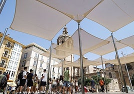 Turistas refugiados en los sombrajes de la plaza de la Reina.