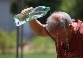 Un hombre mayor, que es el perfil del fallecido, se refresca echándose agua por la cabeza.