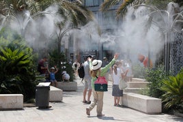 Turistas buscan mitigar el calor gracias al agua vaporizada.