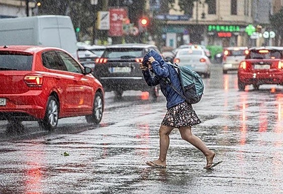 Una chica se intenta refugiar de la lluvia.