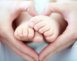 Manos en forma de corazón sosteniendo los pies de su hijo