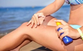 Mujer tomando el sol poniéndose protección solar