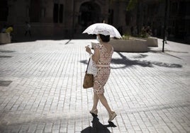 Una mujer se proteje con una sombrilla en Valencia.