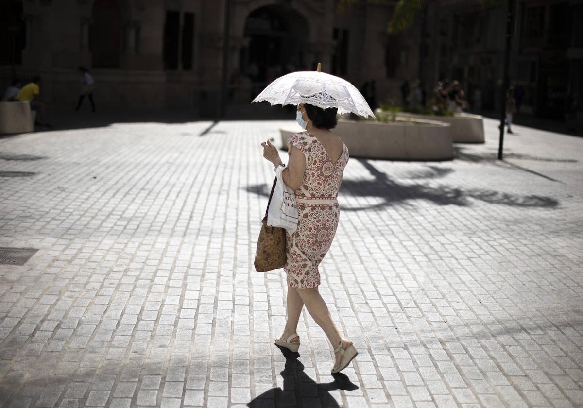 Una mujer se proteje con una sombrilla en Valencia.