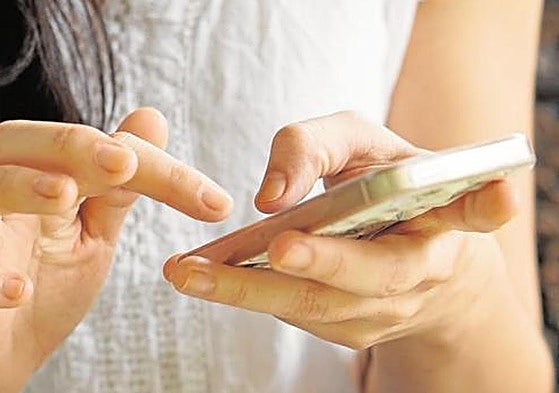 Una mujer consulta su móvil.