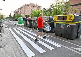 Un hombre cruza un paso de peatones para ir a tirar la basura.