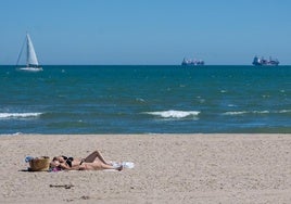 Dos mujeres toman el sol en la playa de Pinedo.