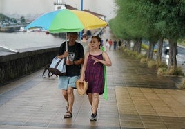 Dos bañistas abandonan la playa por las lluvias.